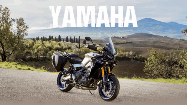 a yamaha motorcycle is parked on a road with mountains in the background