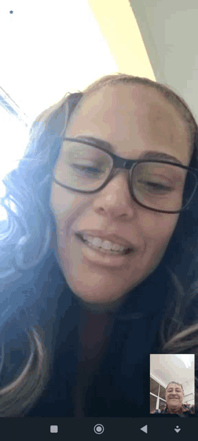 a woman wearing glasses is smiling while talking to a man on a video call