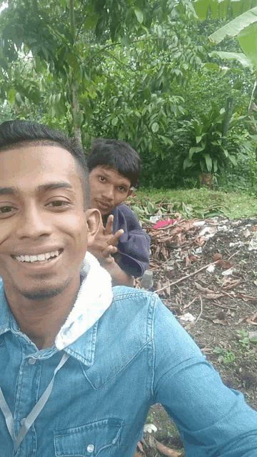 two young men are posing for a picture and one is wearing a blue denim shirt