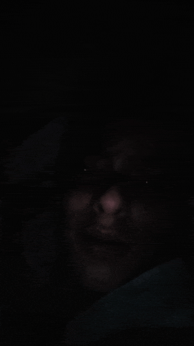 a close up of a man 's face in the dark with his eyes visible