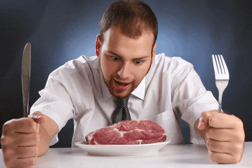 a man holding a knife and fork looks at a plate of raw meat