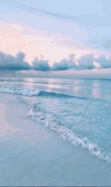 a beach with waves crashing against the shore at sunset