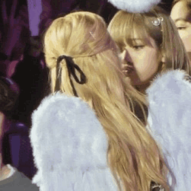 two women are kissing each other while wearing angel wings and a headband .