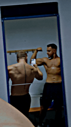 a shirtless man is taking a picture of himself in the mirror