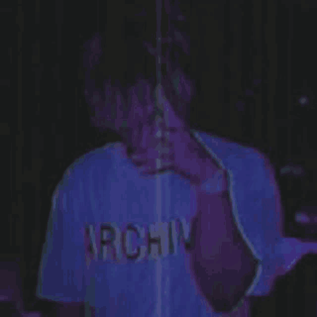 a person wearing a purple shirt with the word archive on it is smoking a cigarette .