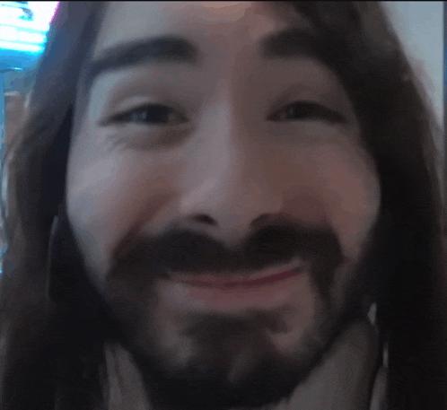 a close up of a man 's face with a beard and long hair