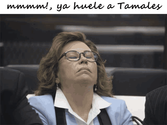 a woman wearing glasses sits with her eyes closed and the words mmmm ya huele a tamales written above her