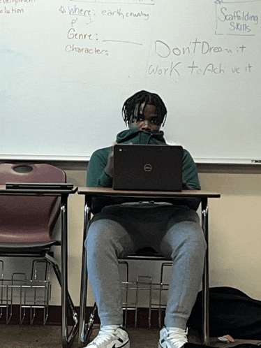 a man sits at a desk with a dell laptop on it