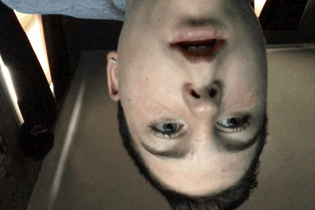 a young boy 's face is upside down and his mouth is open