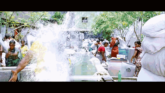 a group of people are standing in front of a water fountain with a bottle of soap in the foreground