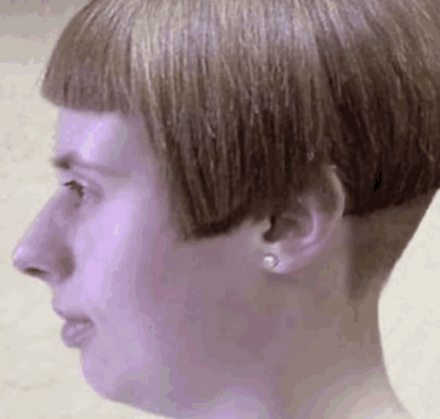 a close up of a woman 's face with a very short hairstyle and earrings .