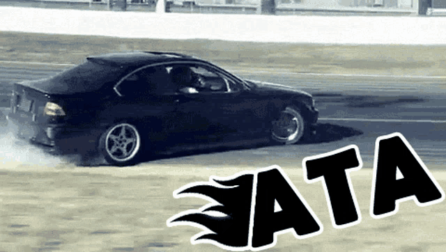 a black car is drifting on a track and the word ata is on the side