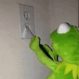 kermit the frog is plugging a wire into an electrical outlet .