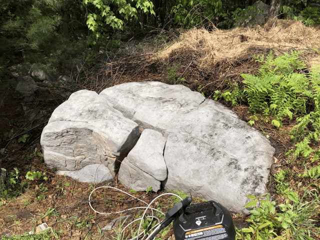 a large rock sits in the grass next to a black item that says ' inverter ' on it