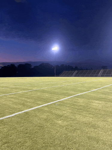 a football field with a stadium in the background at night