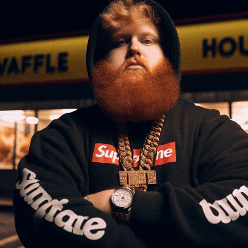 a man with a beard wears a supreme hoodie