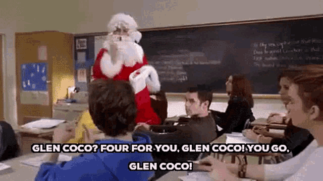 a man dressed as santa claus is standing in a classroom with a group of students sitting at desks .