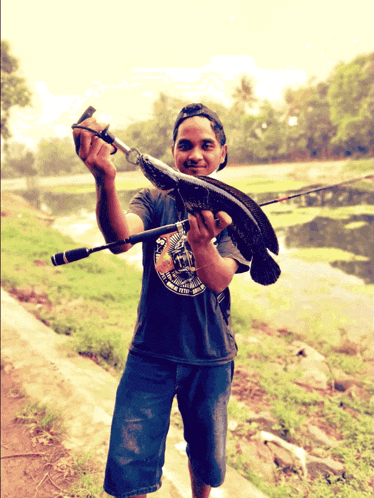 a man holding a fish and a fishing rod with a t-shirt that says " fishing club " on it