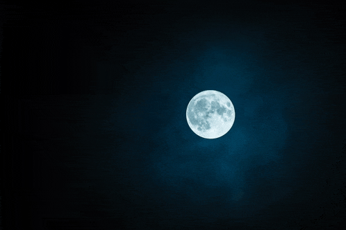 a full moon in a dark sky with clouds