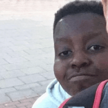 a young boy is making a funny face while sitting next to a man .