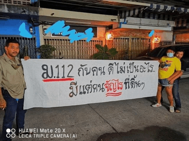 a huawei mate 20 x leica triple camera takes a picture of people holding a large sign