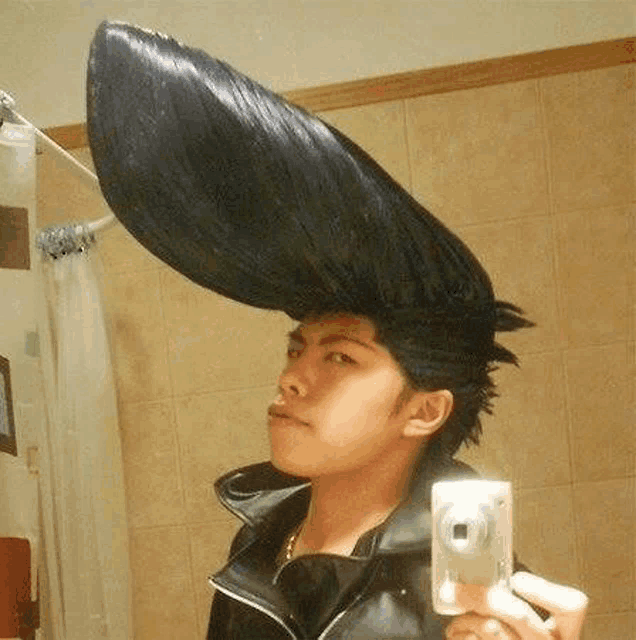 a man is taking a selfie in a bathroom with a very large wig on his head .