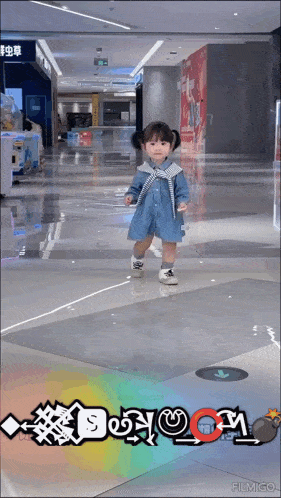 a little girl in a denim dress is standing in a shopping mall with the word boom written on the floor