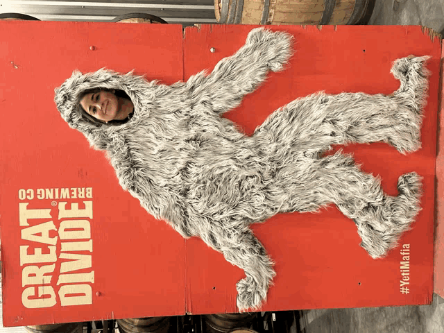 a woman in a bigfoot costume stands in front of a sign that says great divide brewing co