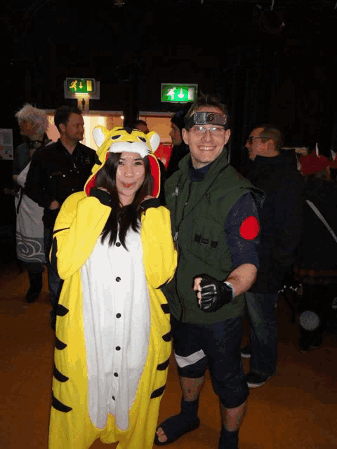 a man in a green vest and a woman in a yellow tiger costume pose for a photo