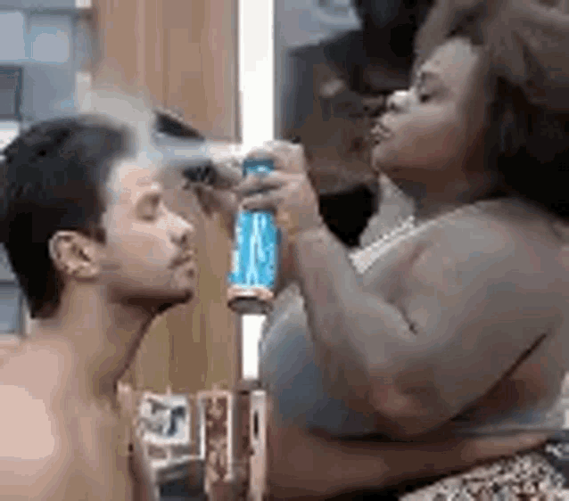 a woman is applying makeup to a man 's face .