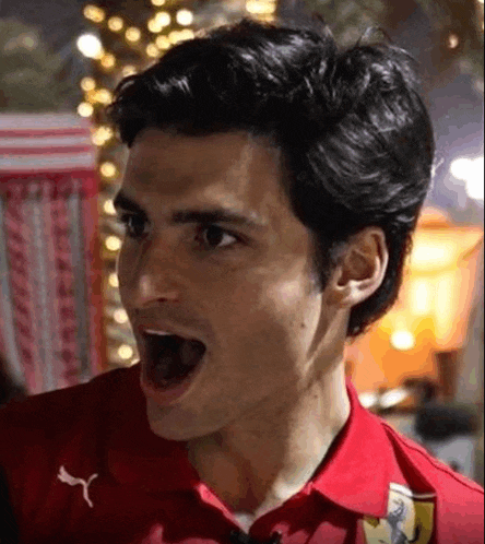 a man wearing a red shirt is making a funny face with his mouth open .