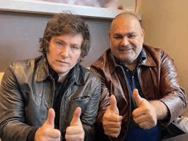 two men in leather jackets are giving a thumbs up sign .