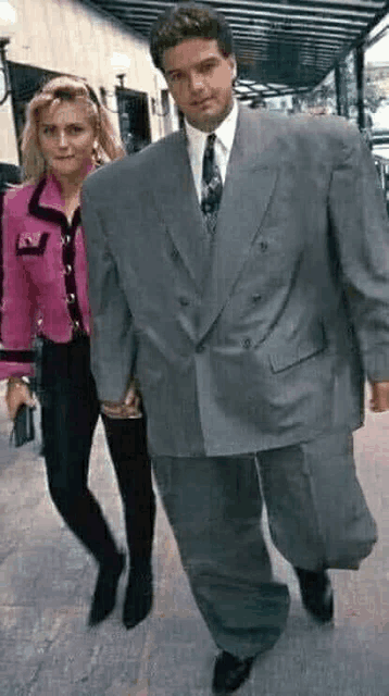 a woman in a pink jacket is standing next to a man in a suit .