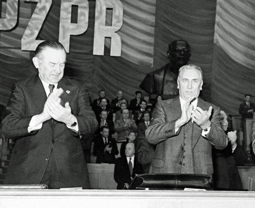 two men applauding in front of a banner that says pzpr