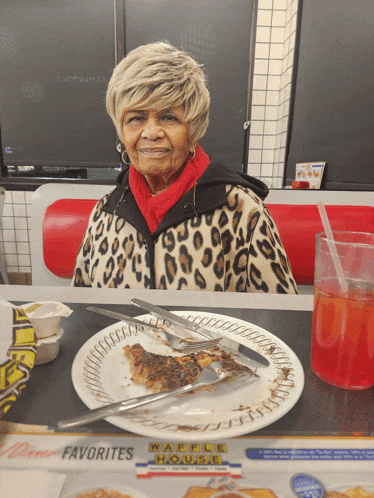 an elderly woman sits at a diner table with a plate of food and a sign that says waffle house