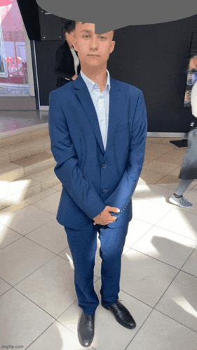 a man in a blue suit is standing with his arms crossed