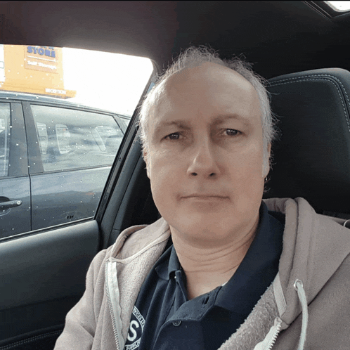 a man sitting in a car with a store sign in the background