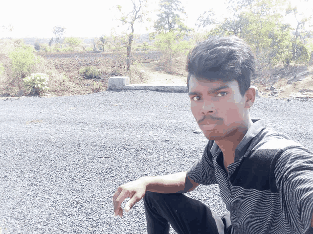 a man in a striped shirt sits on the ground