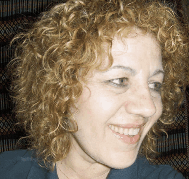 a woman with curly hair is smiling and wearing a blue shirt