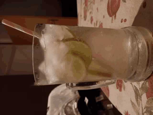 a glass filled with ice and limes with a straw