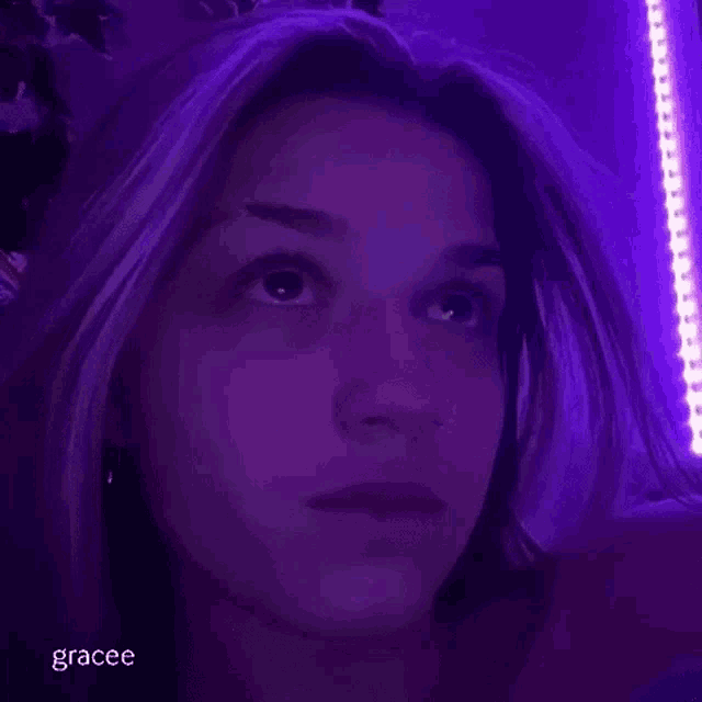 a close up of a woman 's face in a dark room with purple lights .