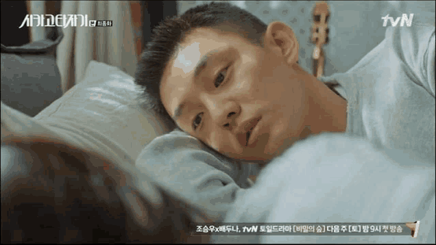 a man is laying on a bed with a tvn advertisement behind him