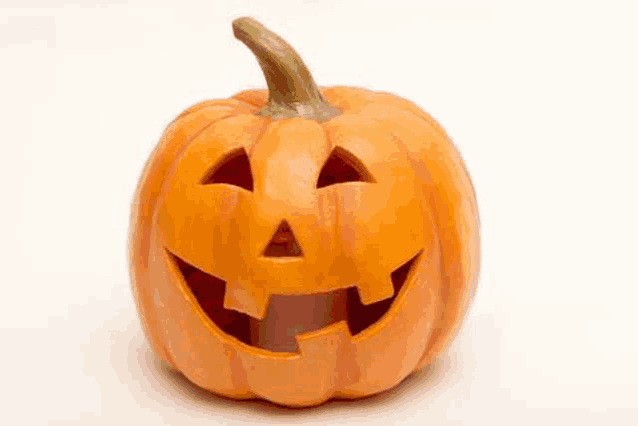 a halloween pumpkin with a face carved into it and a candle inside of it .