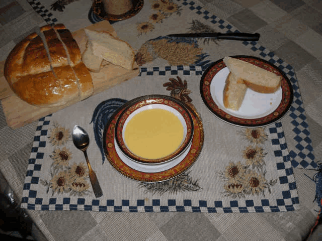 a bowl of soup sits on a placemat next to a plate of bread