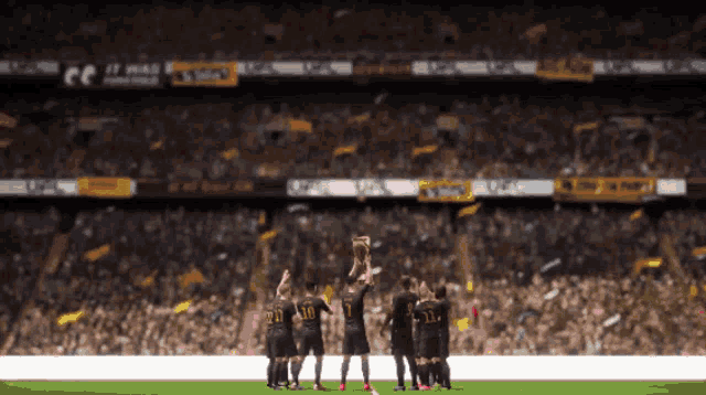 a group of soccer players holding up a trophy in front of a crowd that says ' coca cola ' on it