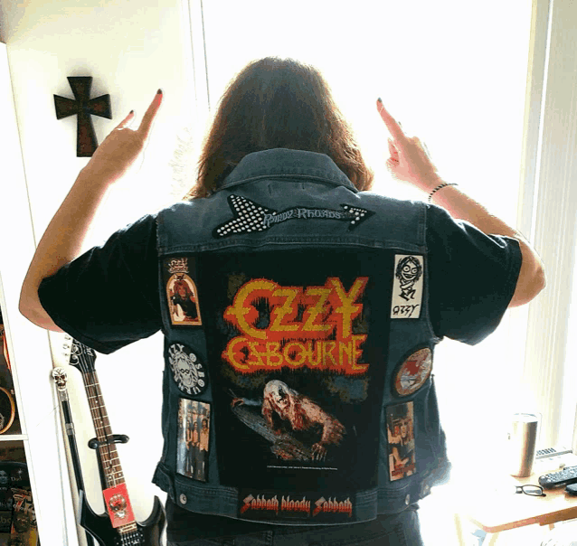 a man wearing a denim vest that says ' ozzy osbourne ' on the back