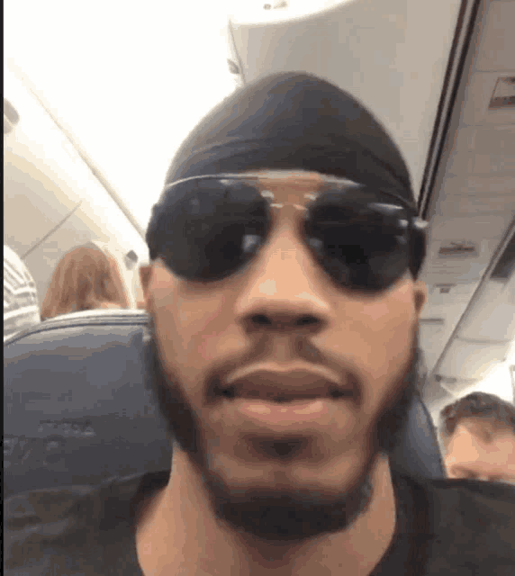 a man wearing sunglasses and a headband on a plane