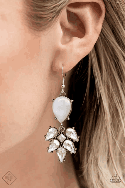 a woman wearing a pair of white earrings with rhinestones on them