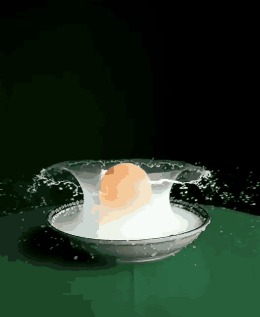 an egg is being splashed into a bowl of milk