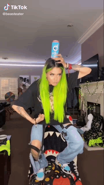 a woman with green hair is holding a can of soda on her head